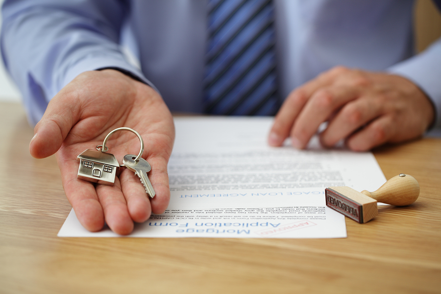 Real estate agent handing over house keys with approved mortgage