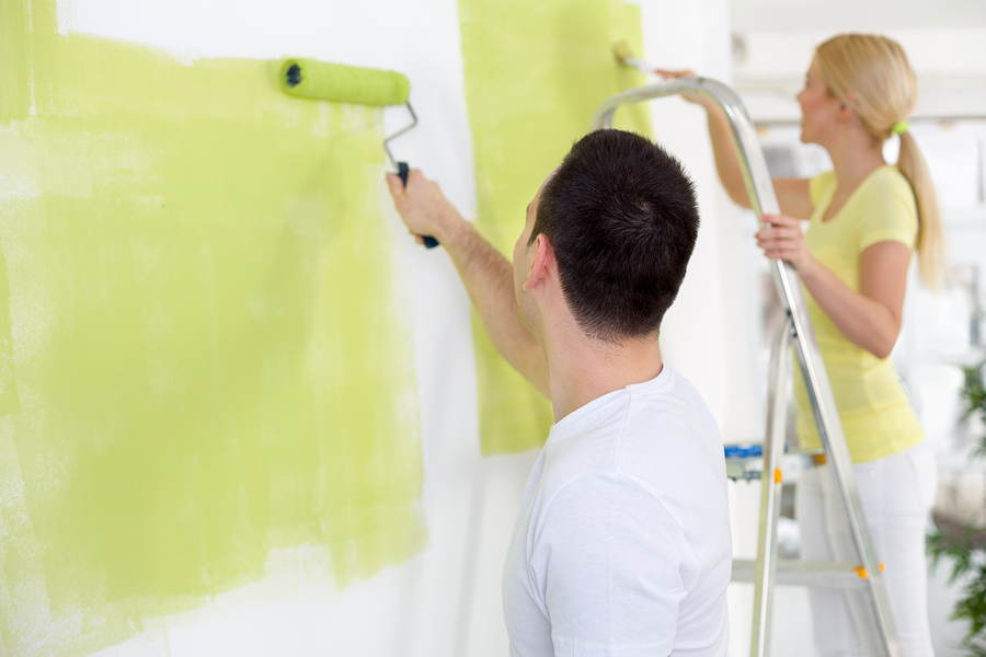 Couple in their new home painting wall in green